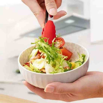 Pince de cuisine rouge en silicone facile à nettoyer sous l'eau, illustrant la simplicité d'entretien après usage.