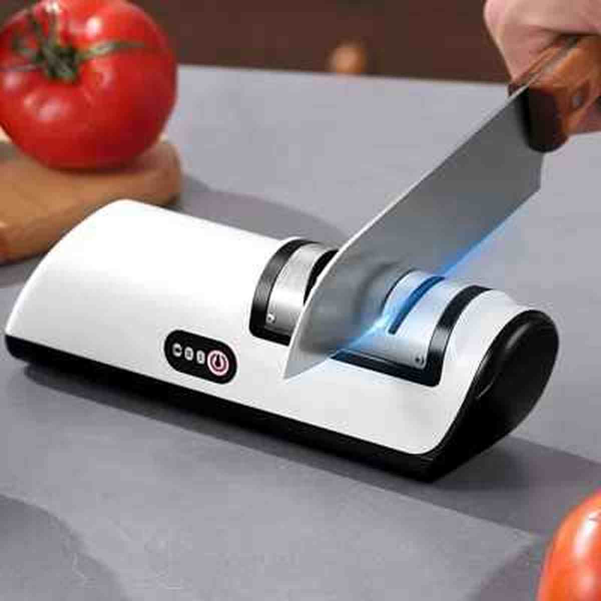 Aiguiseur électrique UltraSharp en action affûtant une lame de couteau de cuisine avec précision, à côté d'une tomate fraîche.