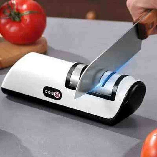 Aiguiseur électrique UltraSharp en action affûtant une lame de couteau de cuisine avec précision, à côté d'une tomate fraîche.