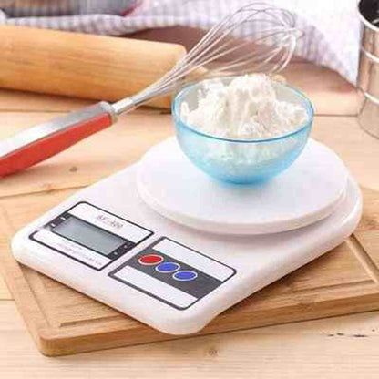 Balance de cuisine blanche Precision Pro avec un bol de farine bleue et un fouet sur une planche à découper en bois.