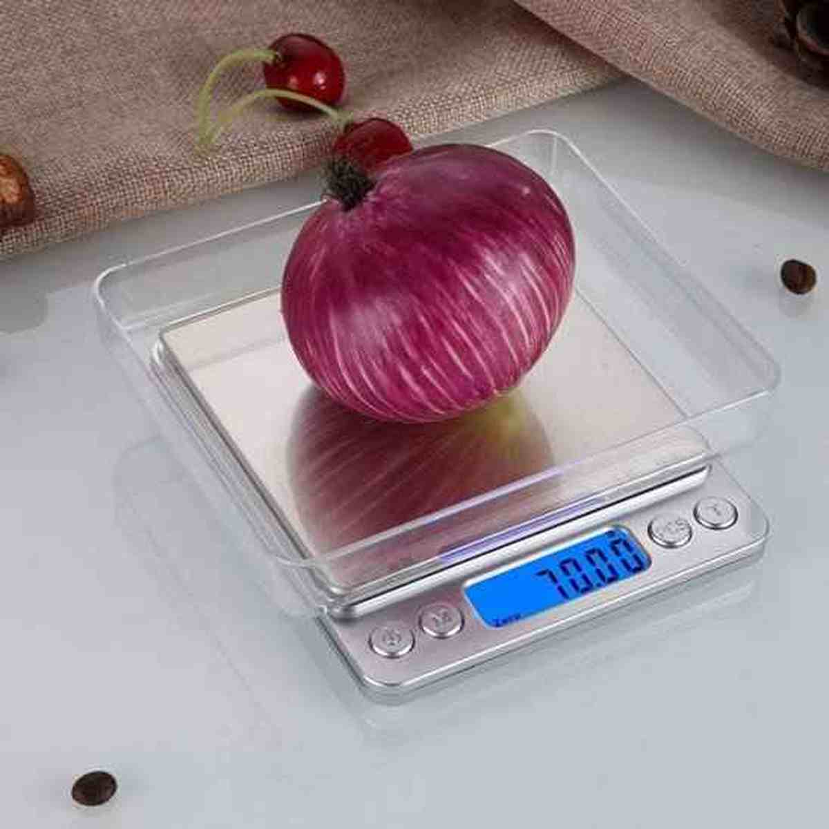 Oignon rouge pesé dans un plateau amovible transparent sur la balance de cuisine électronique en inox, affichant une mesure précise.