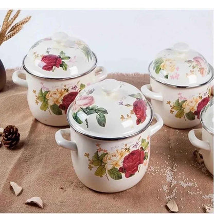 Ensemble de trois casseroles en céramique de différentes tailles avec couvercles, décorées de roses rouges et de fleurs jaunes sur une nappe rustique.