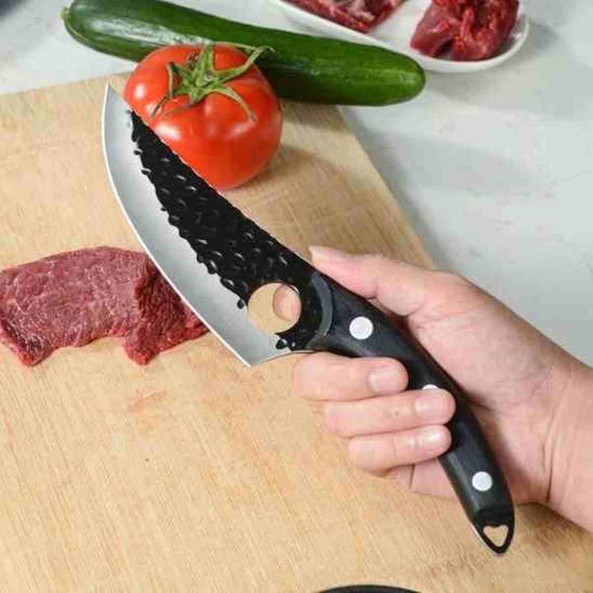 Main tenant le couteau Ultra-Cut avec l'index dans le trou de sécurité pour un contrôle optimal lors de la découpe de légumes.
