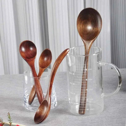Ensemble de cuillères en bois artisanal de différentes tailles présentées dans un verre gradué, parfaites pour le café et le thé