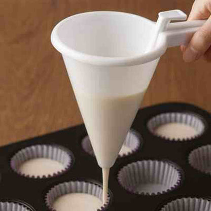 Gros plan d'un entonnoir à piston blanc versant une pâte fluide de manière précise dans un moule à pâtisserie noir.