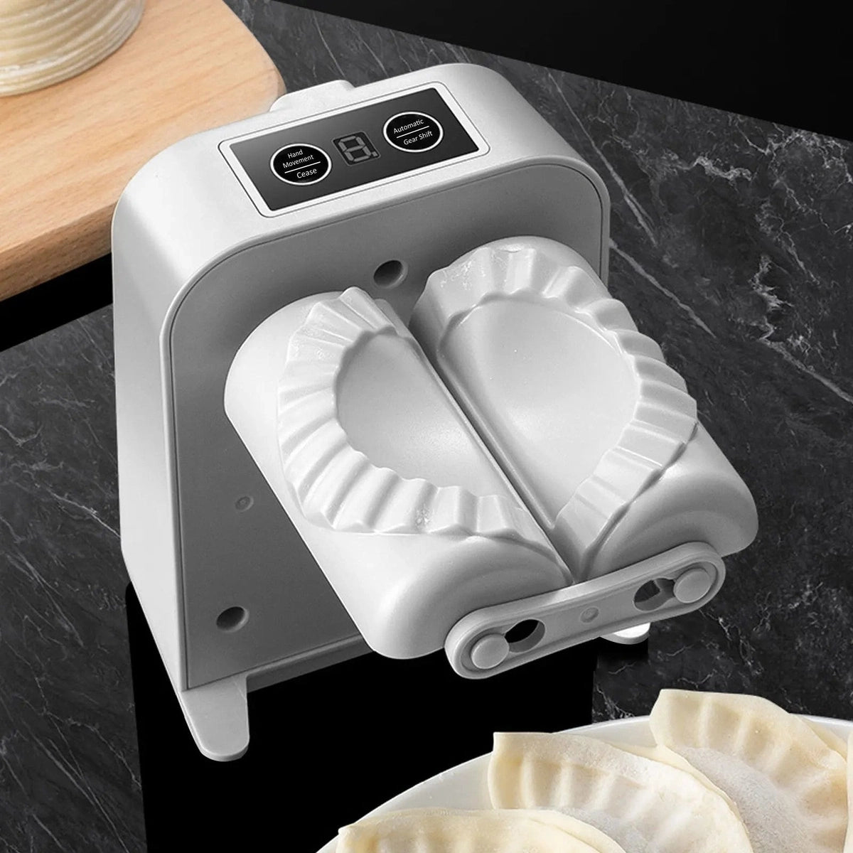 Vue de dessus de l'appareil à raviolis automatique blanc avec des gyozas fraîchement préparés sur un plan de travail noir élégant.