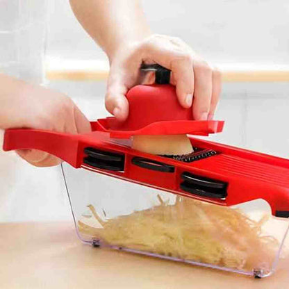 Mandoline de cuisine professionnelle rouge utilisée pour râper des légumes en julienne fine directement dans le bac récupérateur.