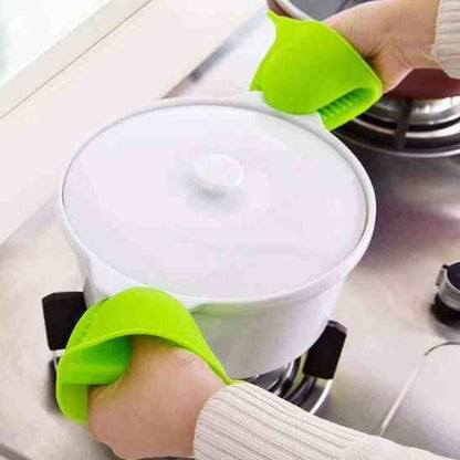 Utilisation de deux mini maniques en silicone vert ThermoShield pour soulever en toute sécurité une cocotte chaude par ses poignées