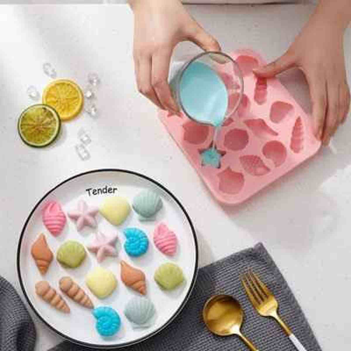 Moule en silicone rose PâtissiPro utilisé pour créer des chocolats et mini-gâteaux en forme de coquillages, avec un aperçu du résultat final coloré dans une assiette