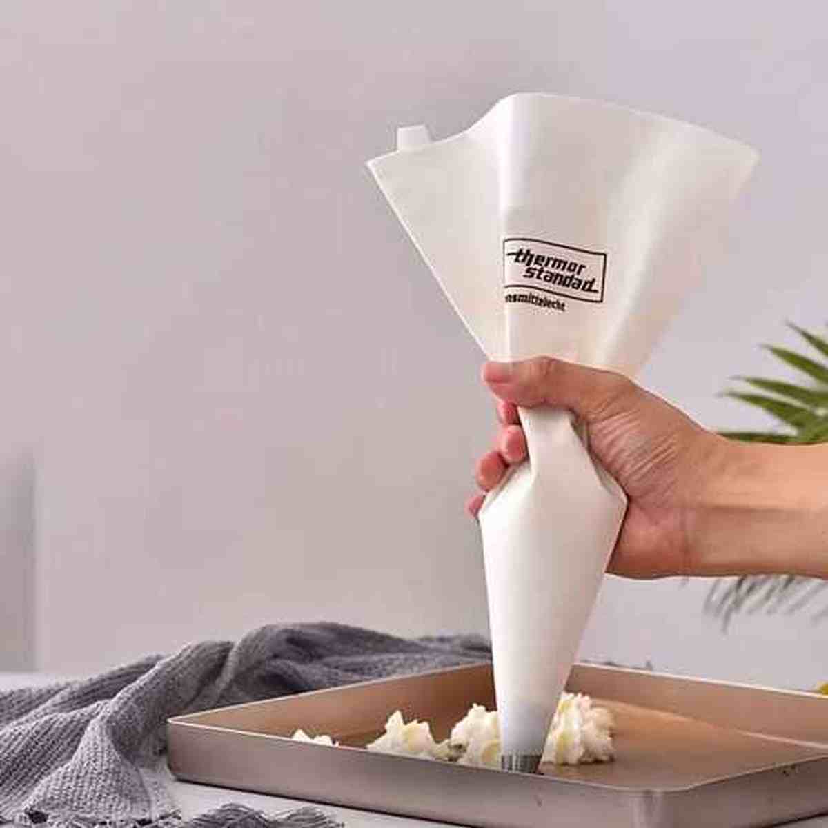 Pochage précis de meringues avec la poche à douille Pâtissier Pro, démontrant la souplesse du silicone et le contrôle parfait du débit
