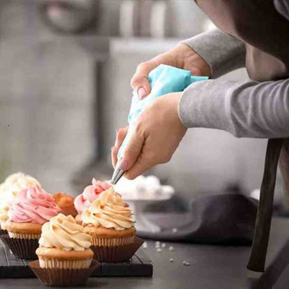 Poche à douille en silicone bleu PâtissiPro utilisée pour glacer des cupcakes avec une crème onctueuse, mettant en avant la précision du kit professionnel.