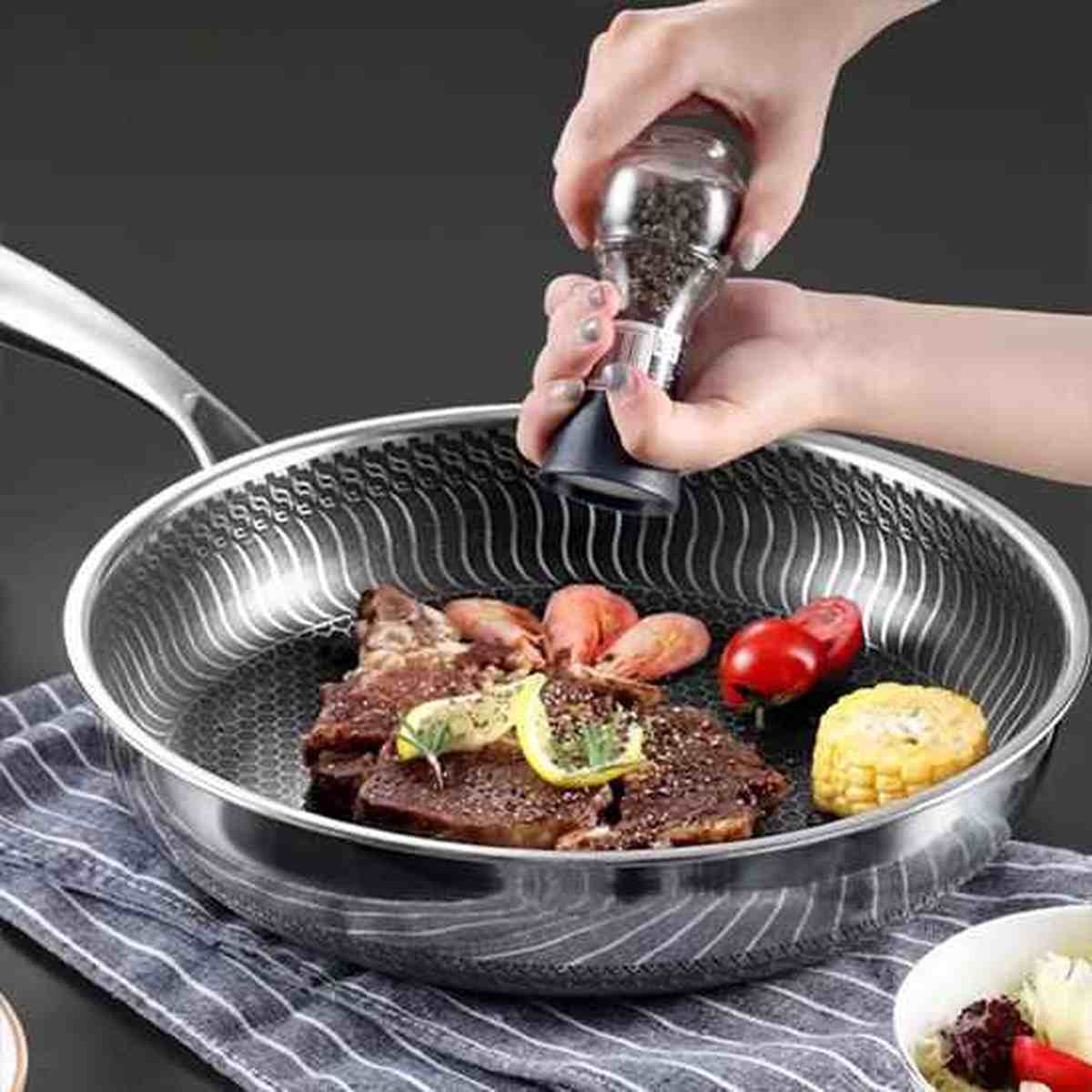 Saisie d'un steak et de légumes dans la poêle en acier inoxydable à fond alvéolé, illustrant la répartition uniforme de la chaleur