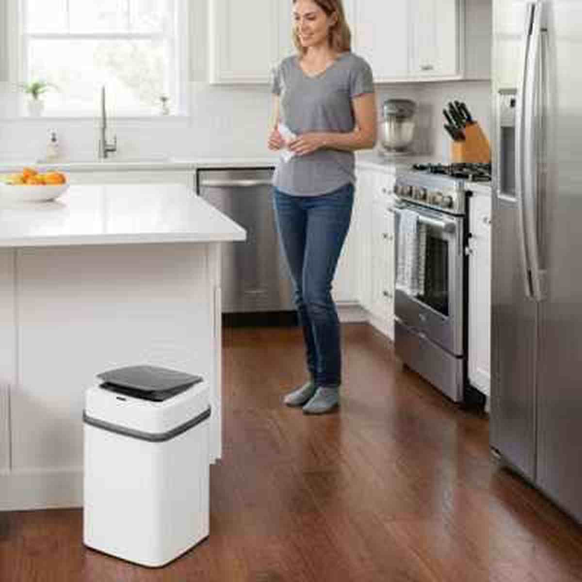 Poubelle automatique blanche Design Fresh placée dans une cuisine moderne spacieuse avec îlot central et électroménager en inox.