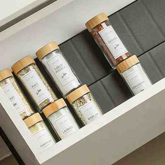 Organisateur de tiroir pour épices extensible OrganizPro avec flacons en verre dans un tiroir de cuisine moderne.